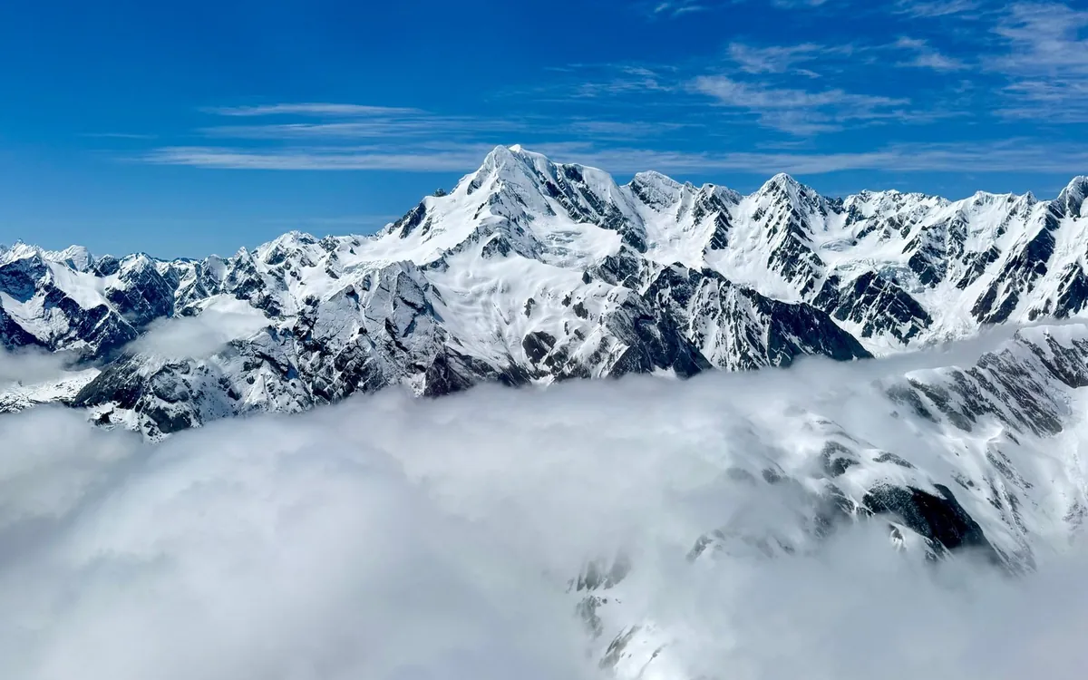 Snow peaks of the Southern Alps rising above a layer of cloud