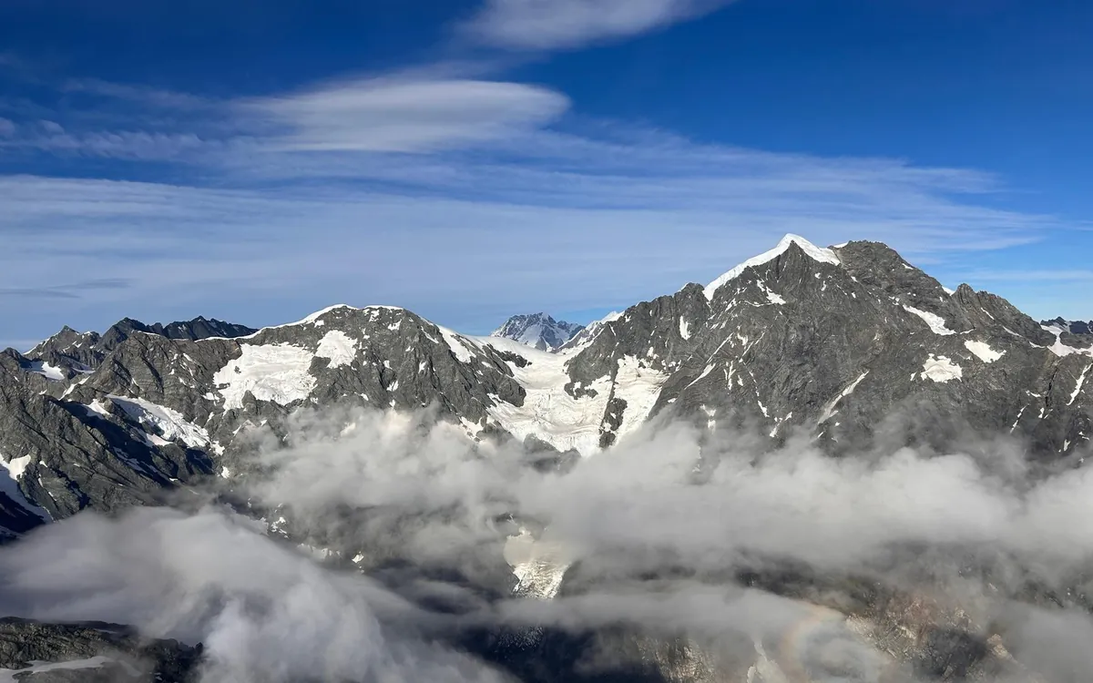 Peaks of the Southern Alps rising through cloud above Franz Josef