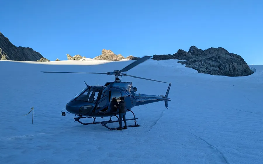 A blue helicopter parked on the snowfield above Franz Josef Glacier