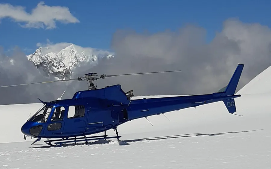 A helicopter flying low over the snowfield above Franz Josef