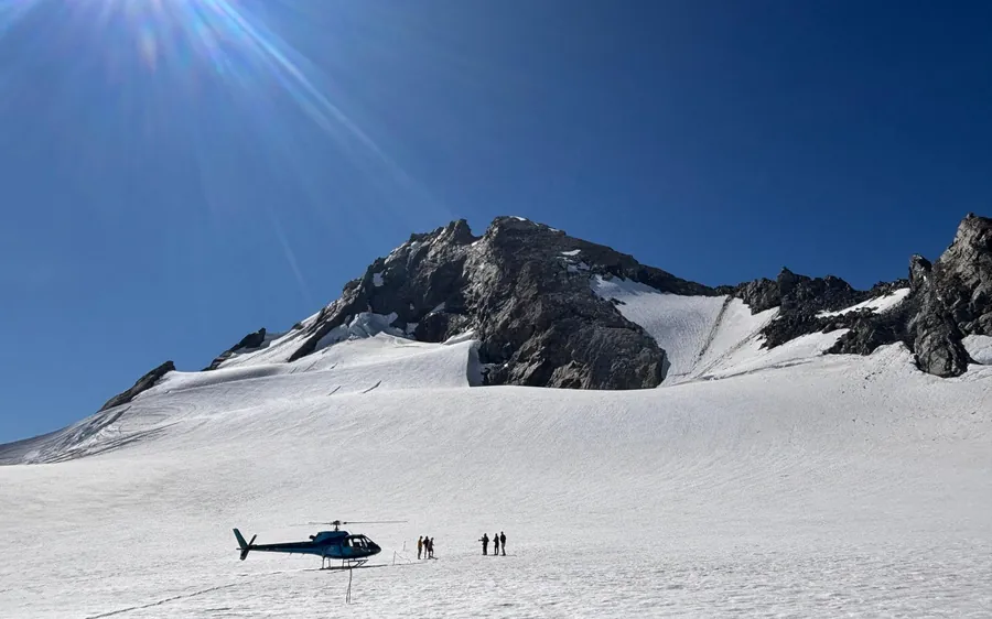 A single helicopter alone on a wide alpine snowfield