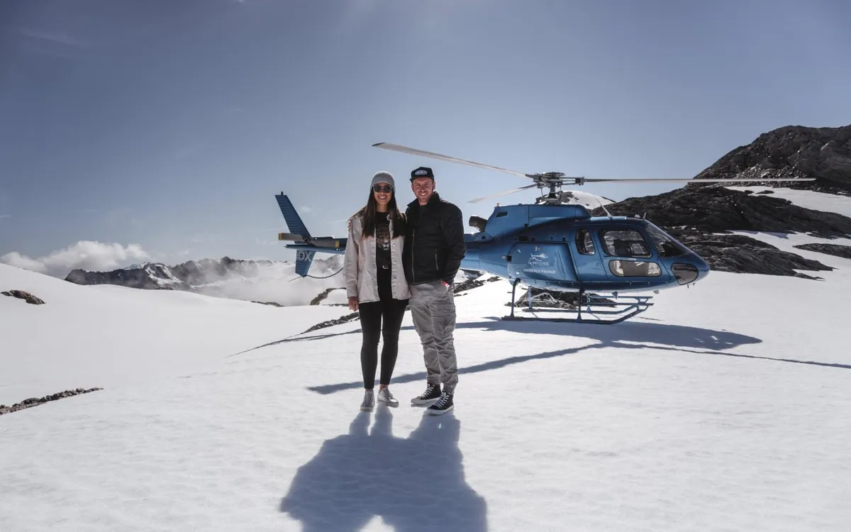 A helicopter on the snowfield with passengers standing beside it